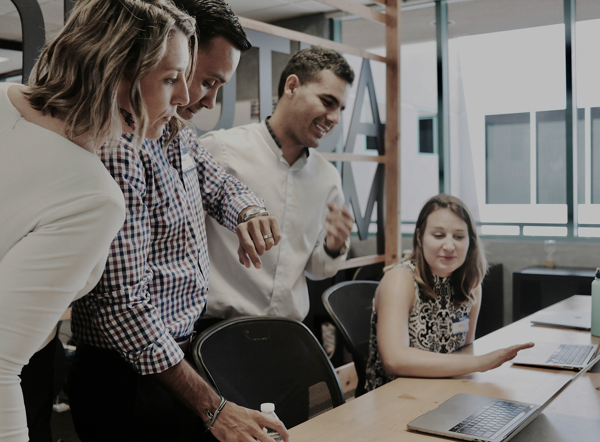 Gespräch zwischen 4 Personen, eine davon sitzt am Laptop