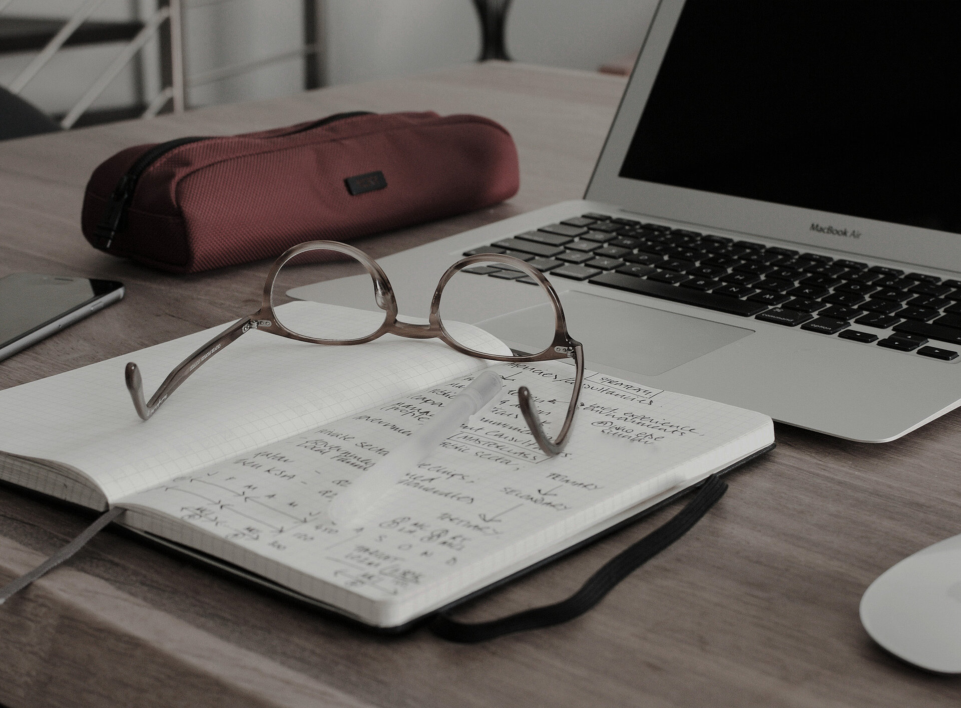 Eine Brille auf Büchern neben einem Laptop