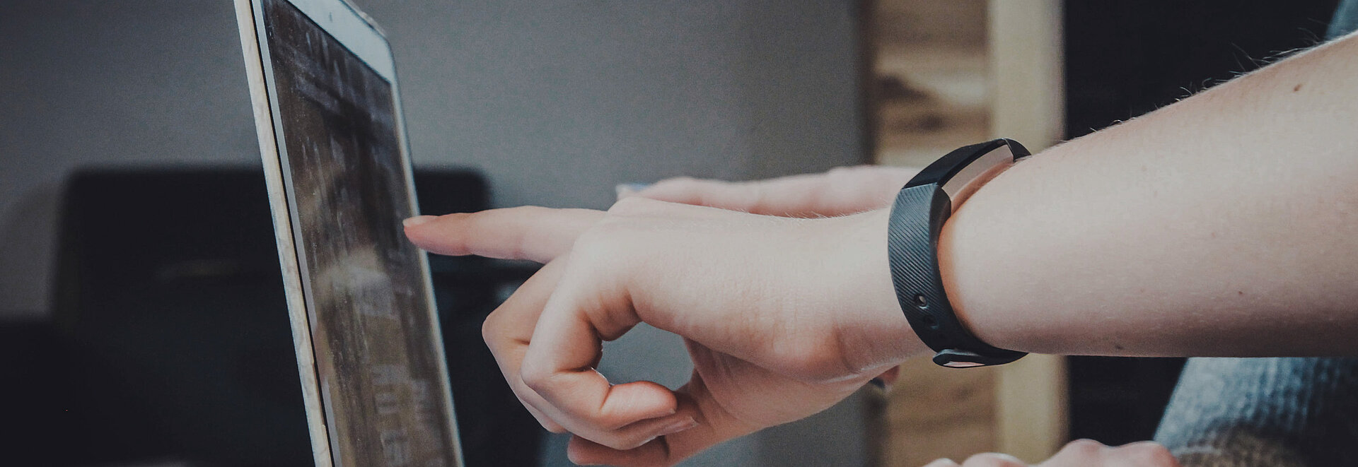 Person zeigt auf etwas auf einem Laptop