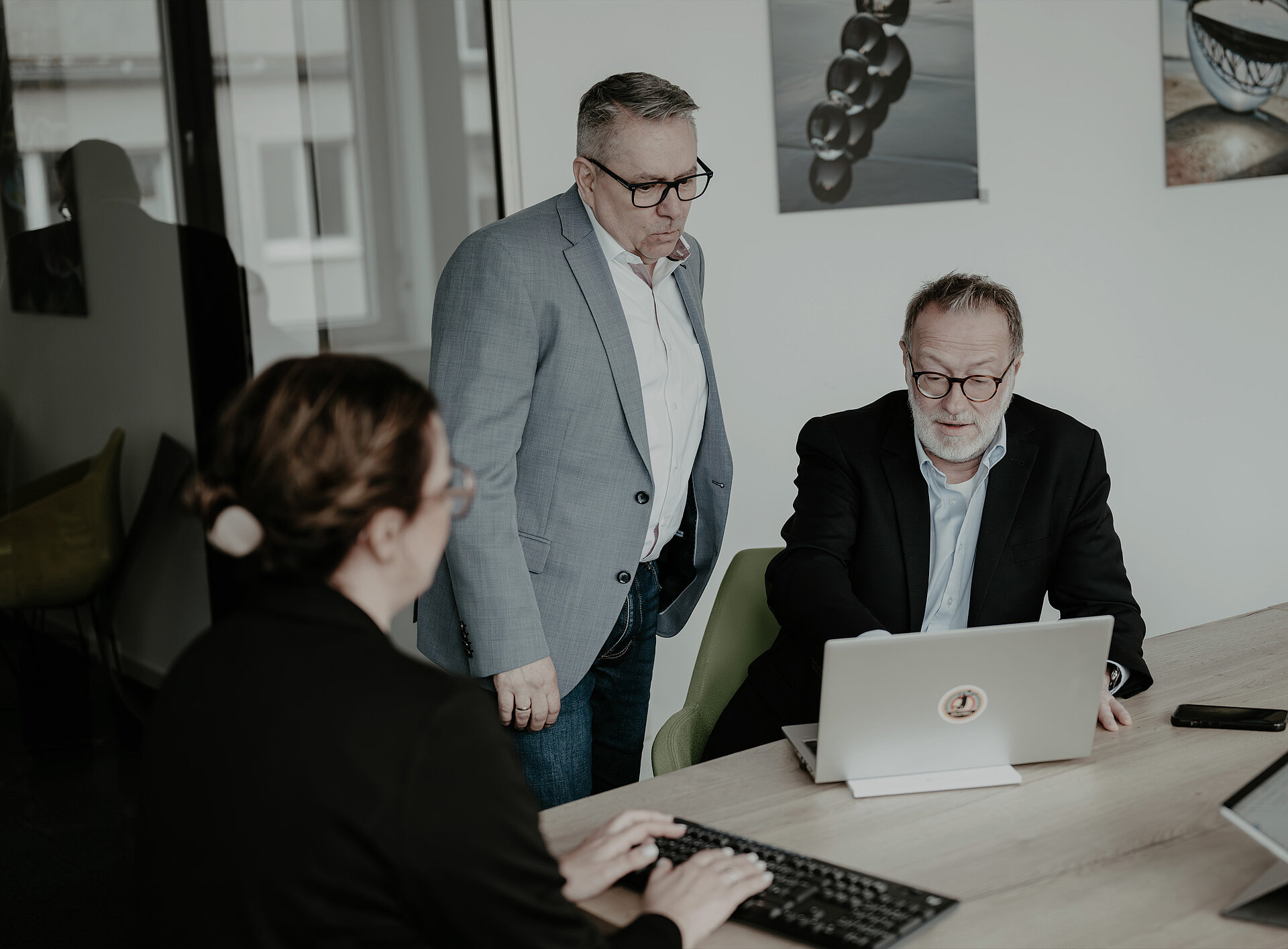 Drei Personen besprechen etwas und schauen auf einen Laptop