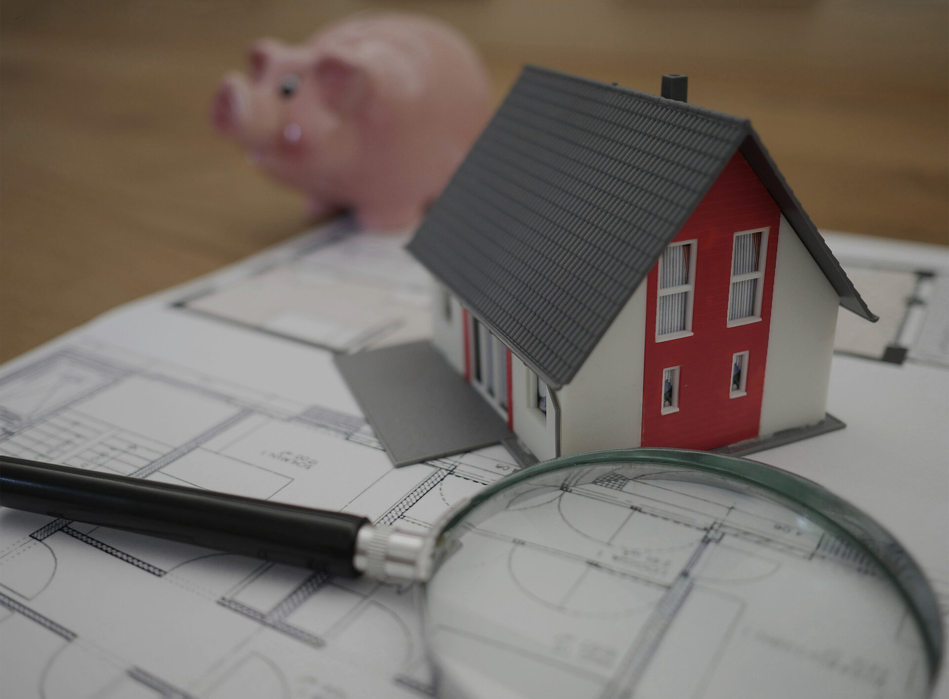 Ein Haus, ein Sparschwein und eine Lupe